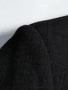 Detailed macro view of the black blazer fabric featuring premium woven cross texture