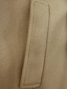Makro-Detailansicht des kamelfarbenen Wollmantels mit präzisen Nähten und hochwertiger Textur