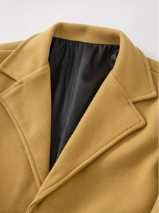 Detail of the notched lapel and mustard wool texture on a stylish long trench coat
