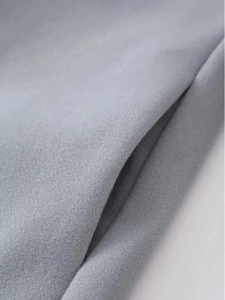 Detail view of light grey wool fabric texture and invisible side pocket of a men's coat