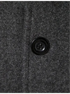 Detailed macro shot of dark grey wool fabric texture and black resin button on coat