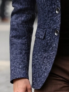 Detailed view of navy blue blazer featuring silver textured buttons and a flap pocket