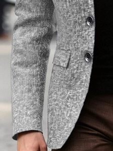 Detail of single-breasted grey blazer featuring a textured finish and classic flap pocket