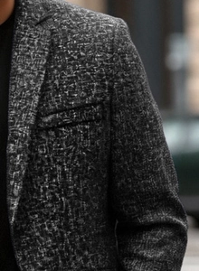 Detail of grey textured woven fabric and shoulder seam on a men's business blazer jacket