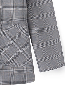 Détail d'un blazer gris à carreaux Prince de Galles montrant le tissu tissé et les poches