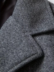 Macro shot of gray wool blend fabric detail and fine stitching on the lapel
