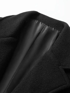 Detail shot of black wool overcoat collar showing fine texture and smooth satin lining