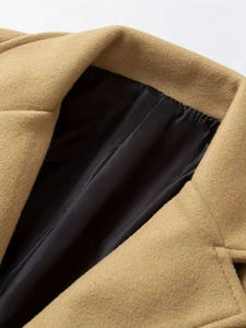 Close-up of camel wool coat lapel featuring premium stitching and black silk lining