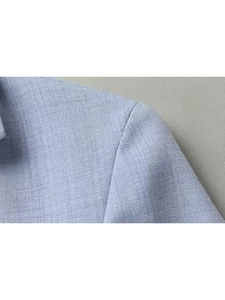 Detail of light blue suit jacket shoulder showing textured fabric and clean seam stitching