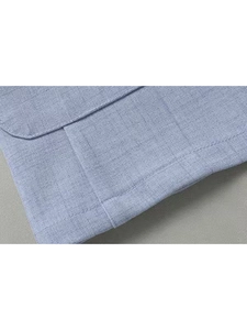 Detailed close-up of blue-grey blazer fabric showing textured weave and premium stitching