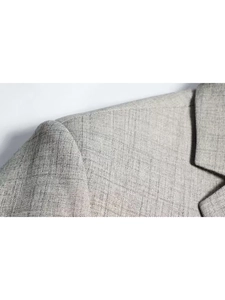Detailed close-up of light gray suit fabric texture with precise shoulder stitching
