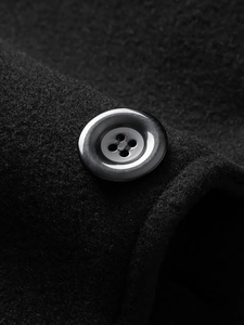 Macro detail of high-gloss button and premium wool texture on long black coat