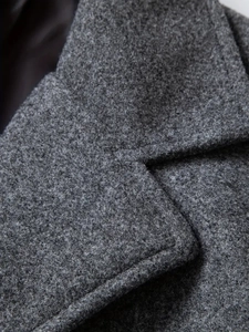 Detailed close-up of dark grey wool blend fabric texture on men's winter coat lapel