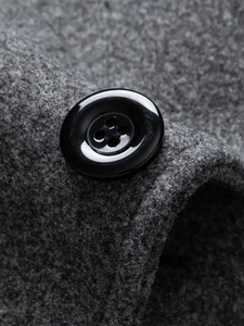 Macro detail of high-quality black button and thick wool fabric texture on gray coat