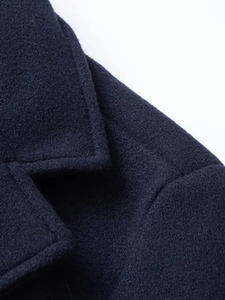 Dettaglio del rever e della spalla di un cappotto di lana blu navy con tessuto pregiato