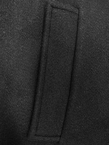 Vista macro dettagliata della tasca a filetto su un cappotto di lana nero da uomo