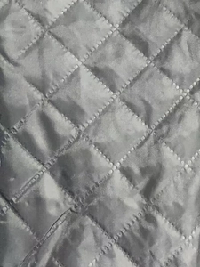 Macro detail of grey quilted lining with diamond pattern and dotted stitching on coat