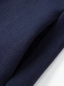 Dettaglio ravvicinato di tessuto misto lana blu navy con trama spessa e cuciture fini