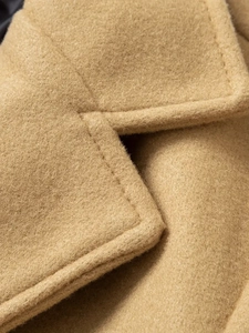 Detail view of high-quality stitching on the collar of a classic men's camel wool coat
