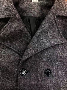 Dettaglio del tessuto del cappotto in tweed grigio scuro con grandi risvolti e bottoni neri