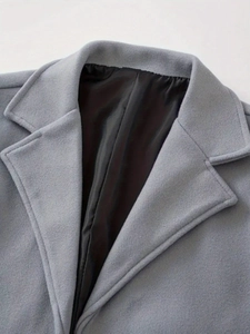 Detail of grey wool coat notched lapel showing premium texture and smooth black lining