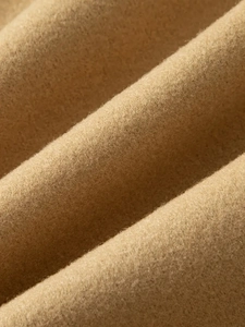 Macro view of camel wool fabric showing dense texture and soft plush feel of the coat