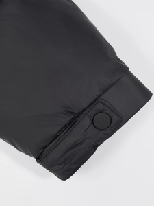 Close-up of black down jacket sleeve featuring windproof fabric and adjustable snap button