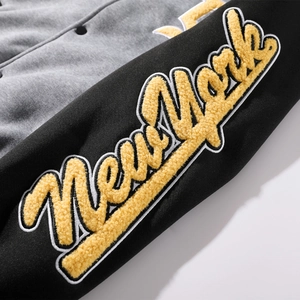 Detail of grey and black varsity jacket with yellow New York chenille embroidery on sleeves