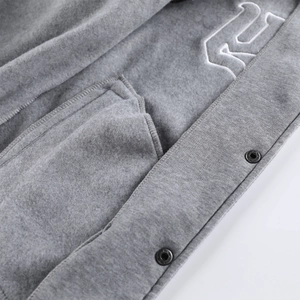 Detail of embroidered RS logo and snap buttons on gray fleece hooded cardigan jacket