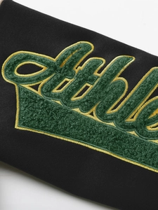 Detail of green and yellow chenille embroidery on a black long sleeve hoodie