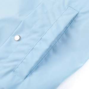 Detailaufnahme der hellblauen Jacke mit Metalldruckknopf und präziser Nahtführung