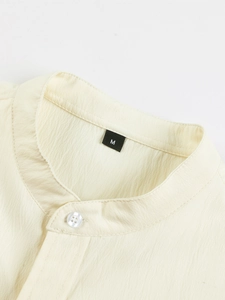 Close-up of textured cotton linen fabric and resin button on a cream Henley shirt