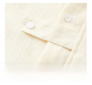 Détail du tissu texturé crème avec patte à double boutonnage et finition froissée