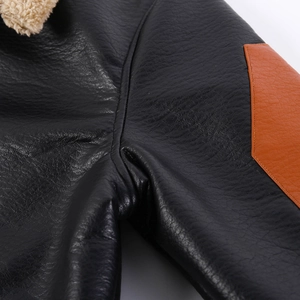 Dettaglio macro della giacca in pelle nera con toppa arancione e fodera in pile felpato
