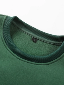 Detail of a dark green sweatshirt showing the ribbed crew neck and soft fleece interior