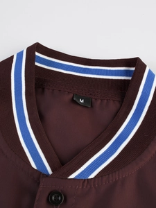 Detalle de una camisa marrón con cuello en V y ribete elástico en azul y blanco
