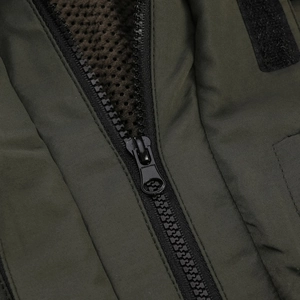 Detail shot of black resin zipper with breathable honeycomb mesh lining in olive green jacket