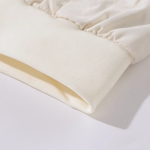 Detail der hochdichten Rippbündchen und der cremefarbenen Stoffstruktur der Baseballjacke