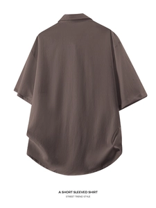 Macro detail of the curved hem on a brown textured short-sleeve shirt for men