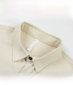 Gros plan du col de chemise beige pour hommes avec design pointu et bouton noir