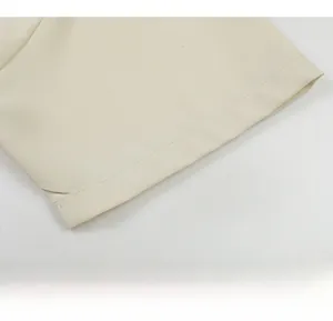 Gros plan détaillé de la manche de chemise blanc crème montrant la couture fine et le sergé