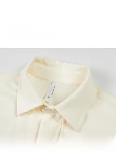 Detail shot of men's beige shirt showing textured fabric collar and size L label