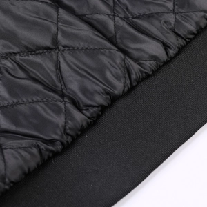 Detailed macro view of black quilted diamond fabric and rib-knit cuffs on baseball jacket