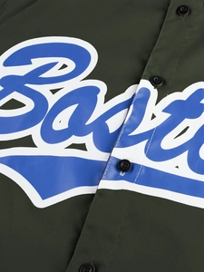 Vista macro detallada de la tela de camisa verde oscuro con logo artístico azul