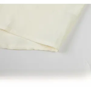 Detail of loose-fit summer shirt featuring a curved hem and textured cream fabric