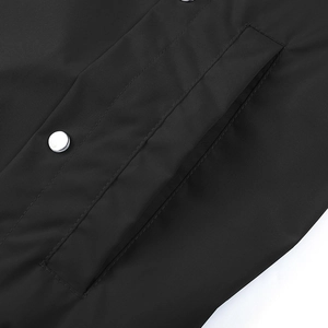 Detail der wasserdichten schwarzen Baseballjacke mit Metalldruckknöpfen und Taschennähten