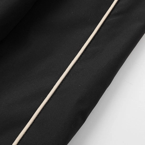 Detailed macro view of black twill fabric with white decorative piping on the jacket sleeve
