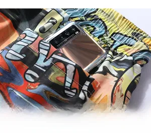 Detail of printed beach shorts featuring a large side patch pocket holding a smartphone