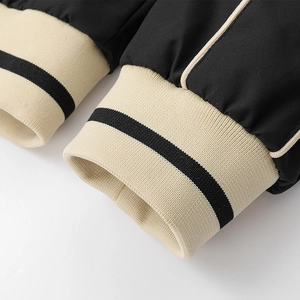 Detailed close-up of ribbed cuffs with contrast stripe on black casual jacket