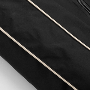 Close-up of waterproof black nylon fabric with double beige piping and resin zipper detail